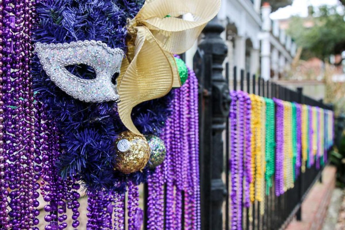 masquerade masks with beaded necklaces on a fence
