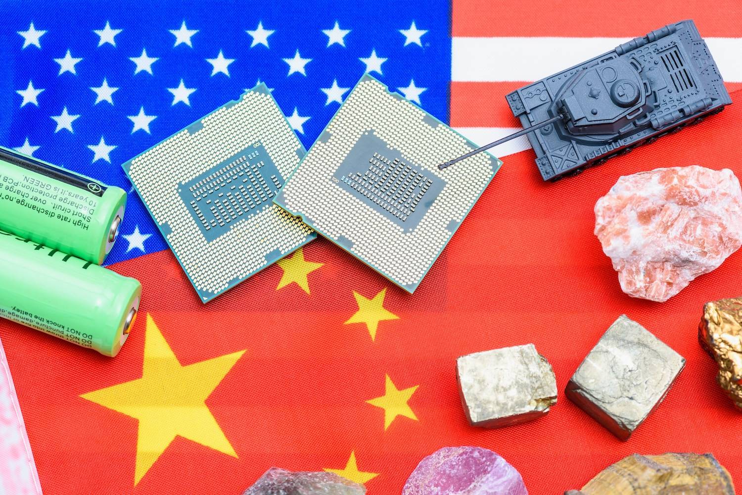 Microchips, ore, batteries and a toy tank on overlapping US and Chinese flags.