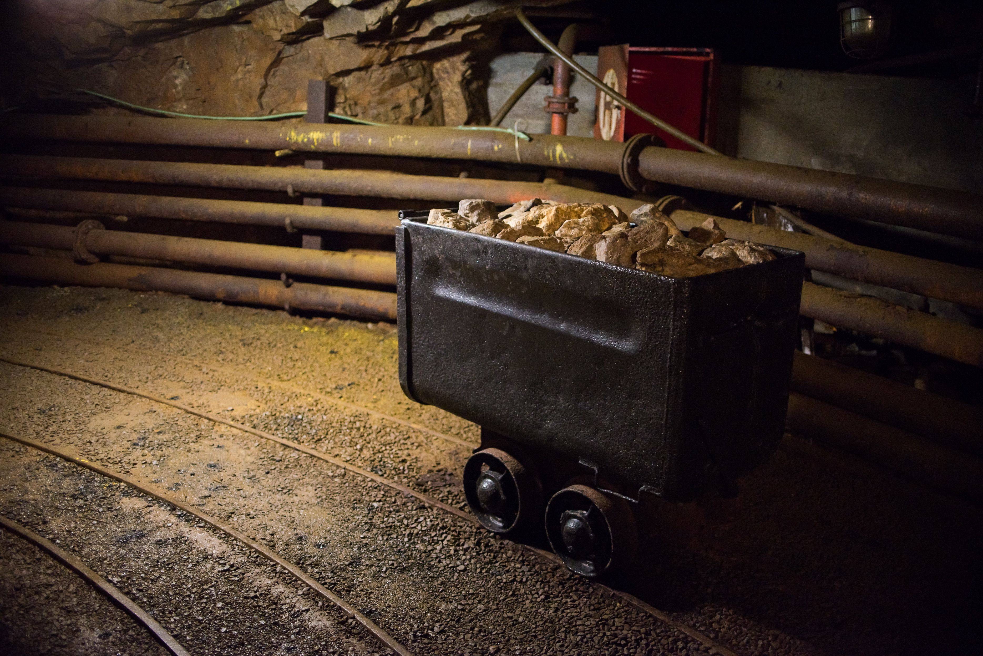 Mining cart filled with rocks on tracks in an underground tunnel.