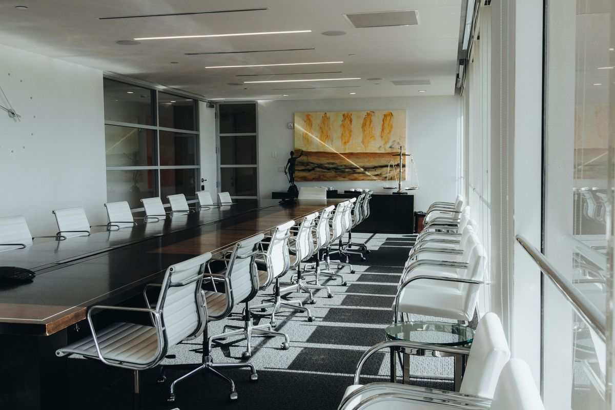 Modern conference room with a long table, leather chairs and abstract wall art.