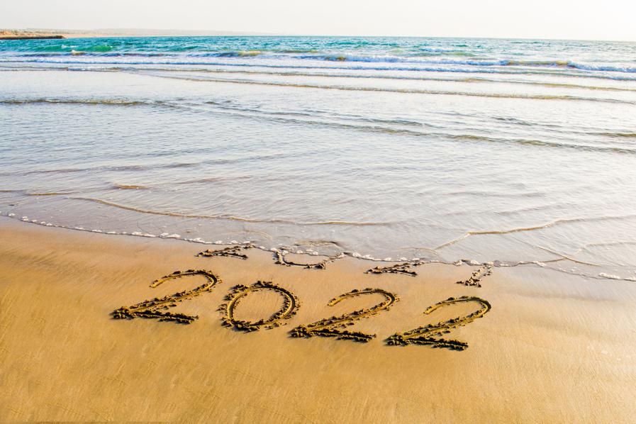 ocean washing away "2021" in the sand, leaving "2022" untouched