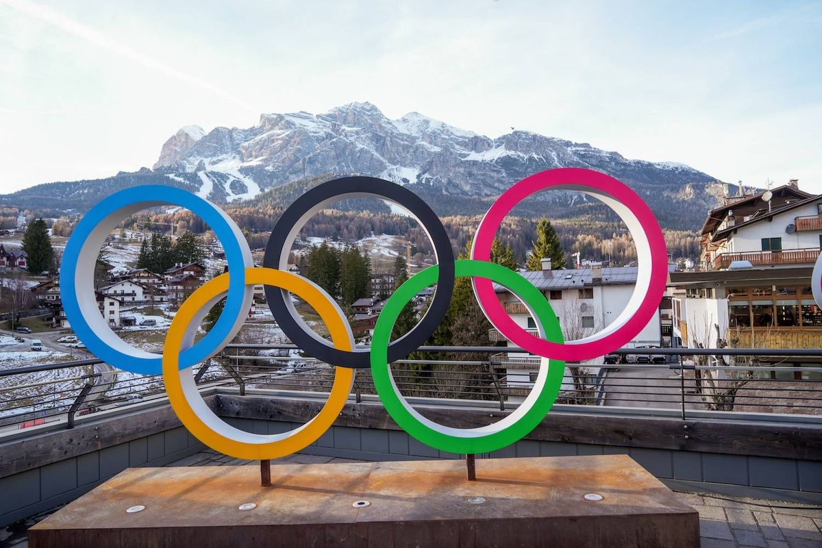 Olympic rings sculpture with snowy mountain backdrop.