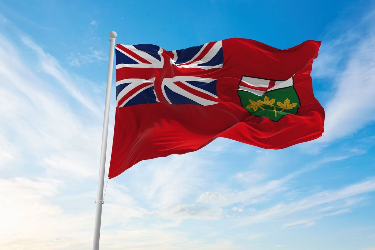 Ontario provincial flag waves against a blue sky.