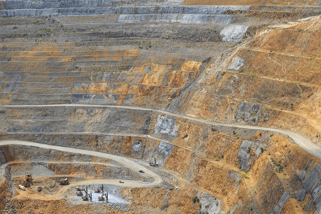 Open-pit mine with steep terraced walls and visible excavation machinery.