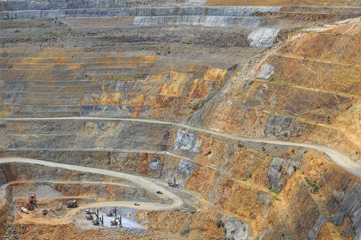 Open-pit mine with steep terraced walls and visible excavation machinery.