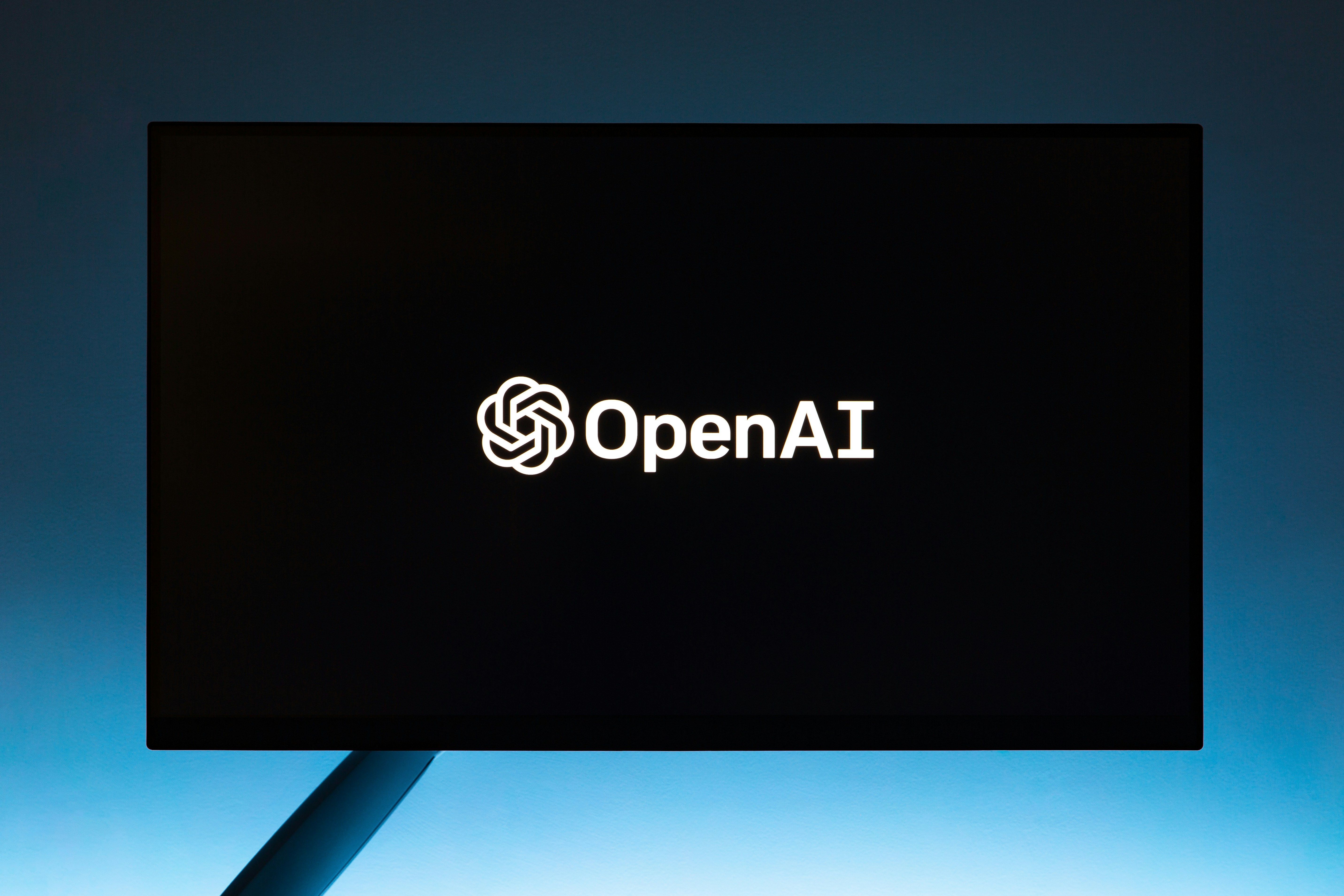OpenAI logo on a dark screen with a soft blue gradient background.