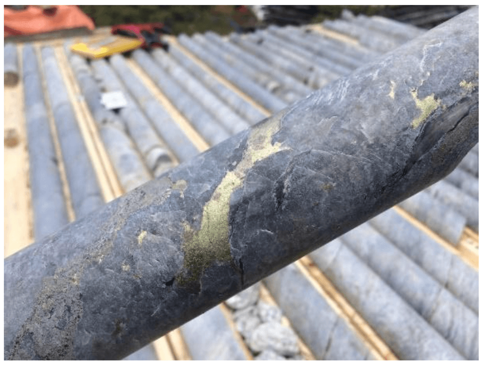 Oreterra Metals' close-up of a rock core sample with metallic mineral streaks, stacked on a wooden rack.