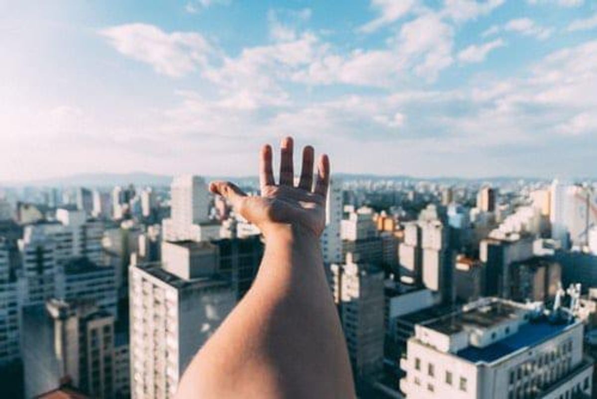 outreached hand above skyscrapers