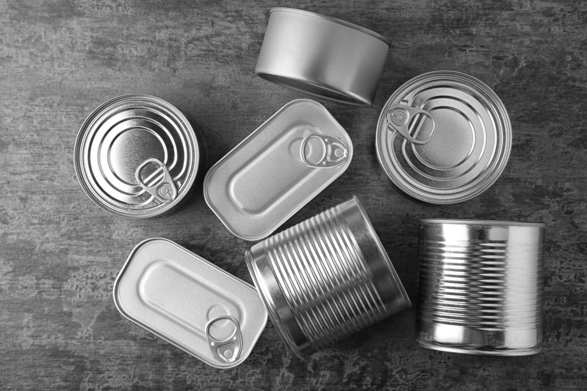 Overhead view of various types of silver tin cans on a grey surface.