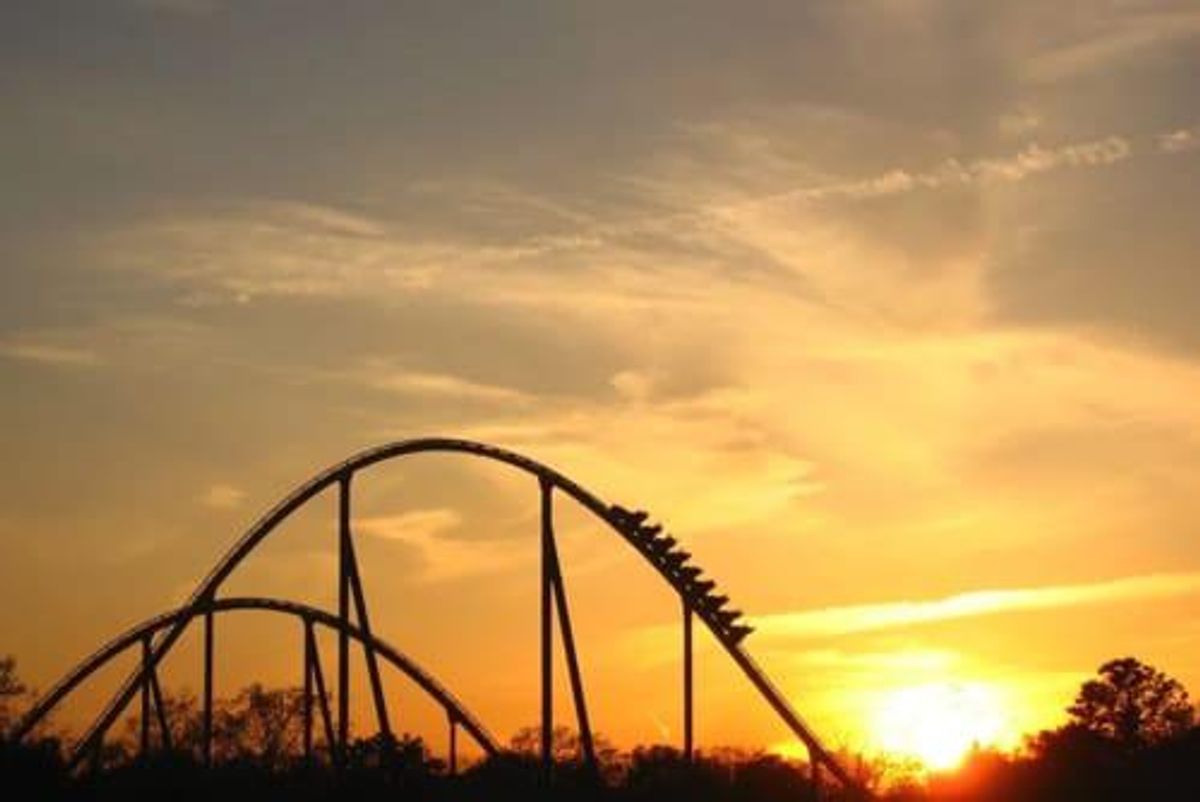 people going up a peak on a rollercoaster with a sunset in the background