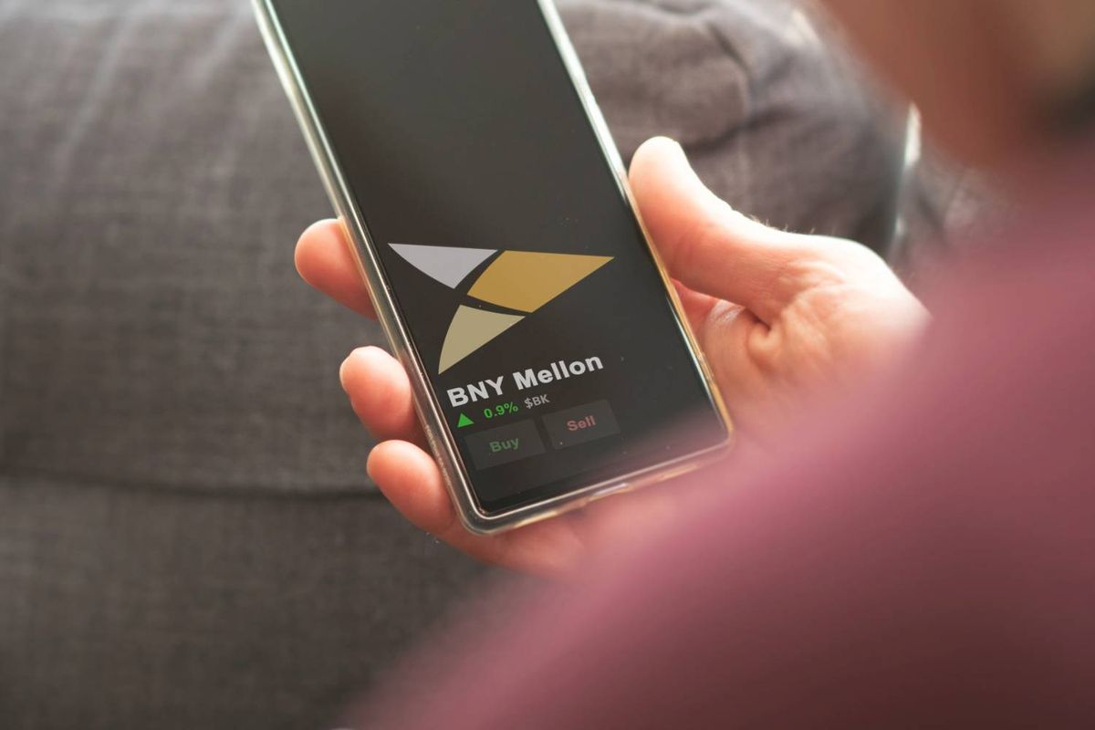 Person holding a smartphone showing BNY Mellon stock information.