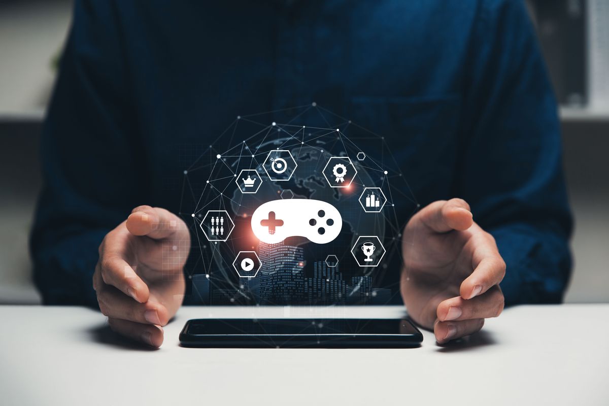 Person holding virtual game icons over a smartphone screen.