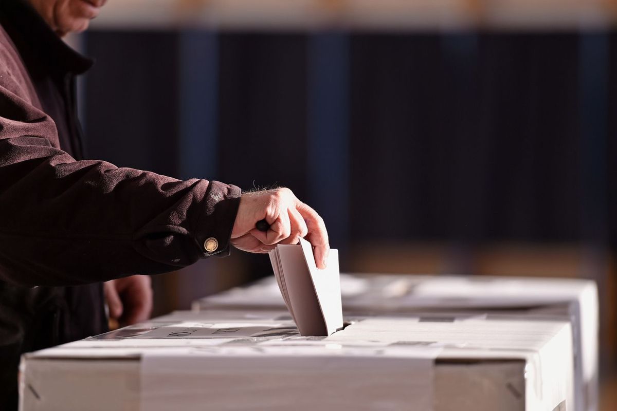 Person placing a ballot in a voting box.