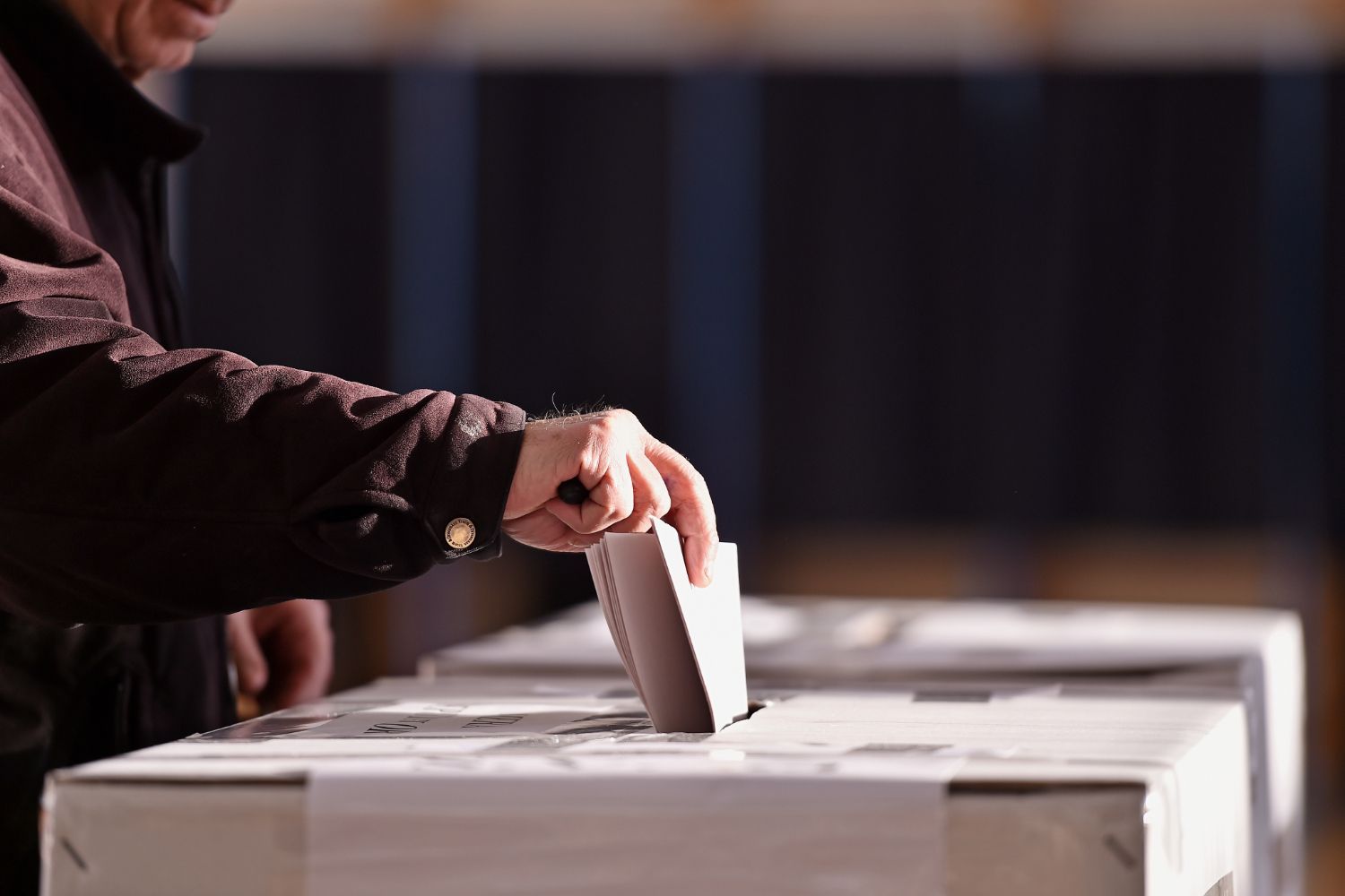 Person placing a ballot in a voting box.