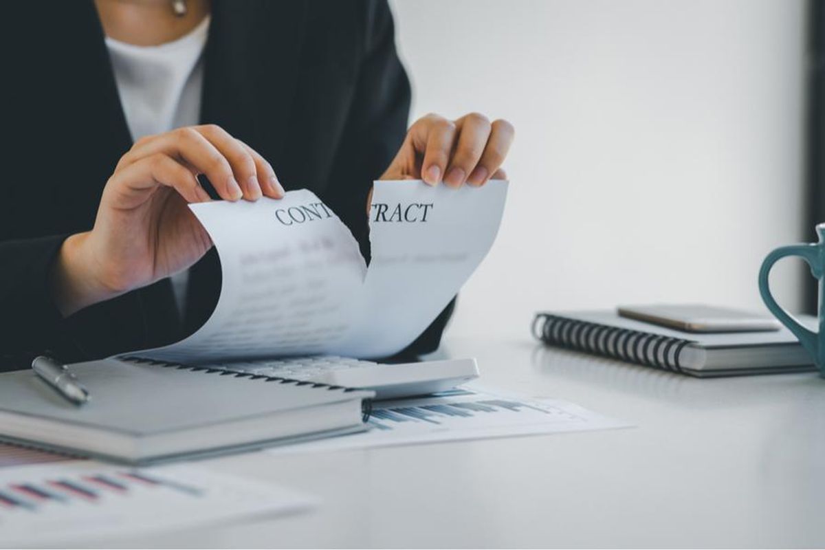 person ripping business contract in half
