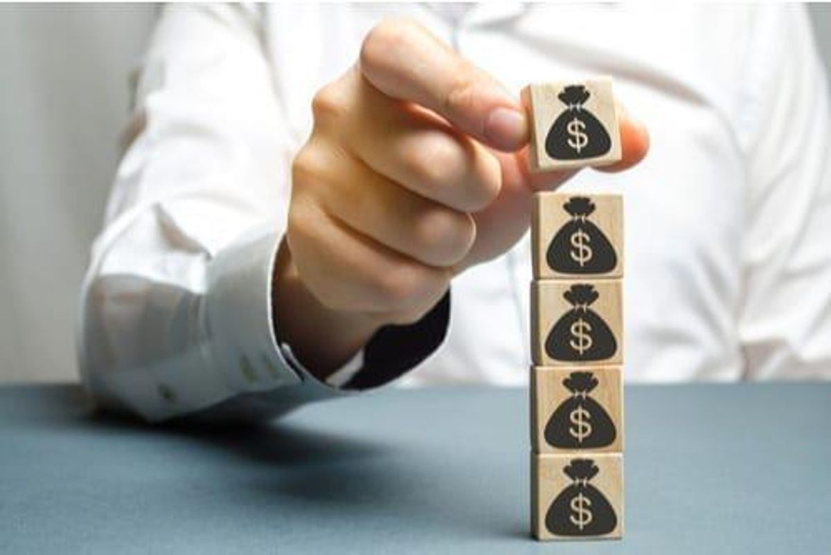 person stacking blocks with money bags