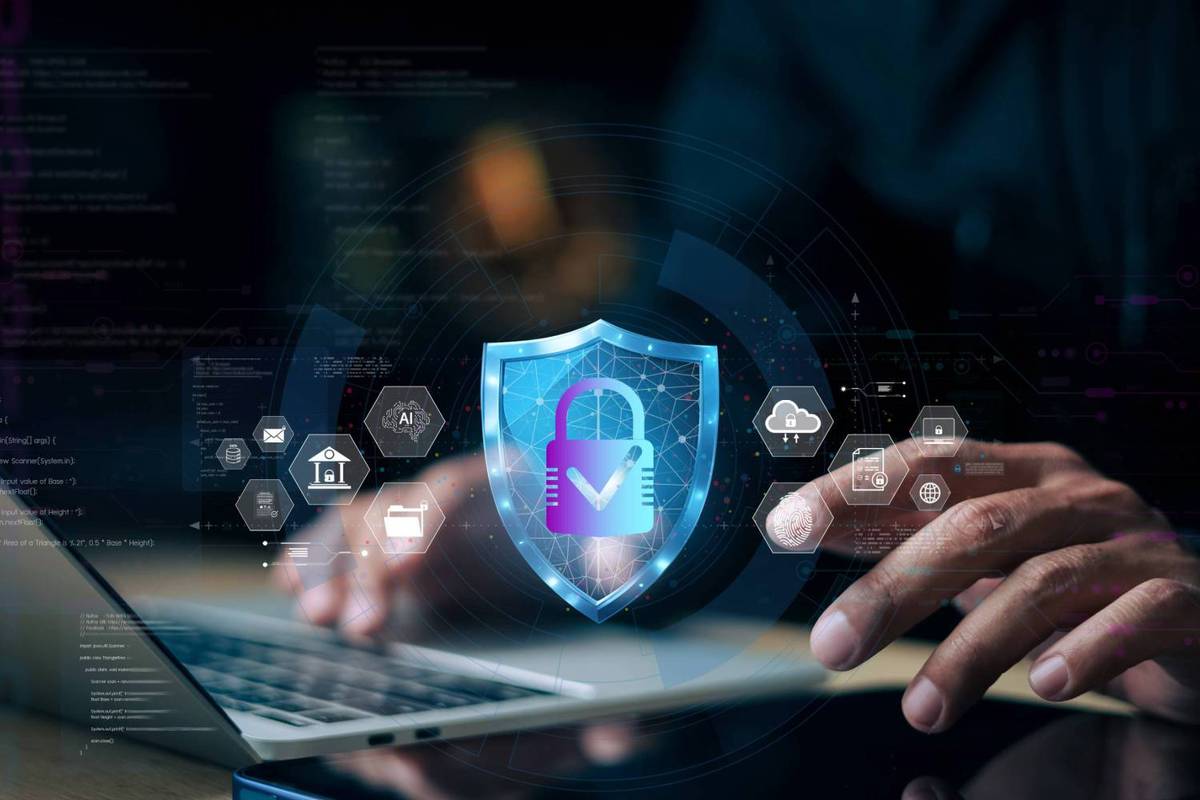 Person types on a laptop with a holographic shield displaying a padlock and network icons.