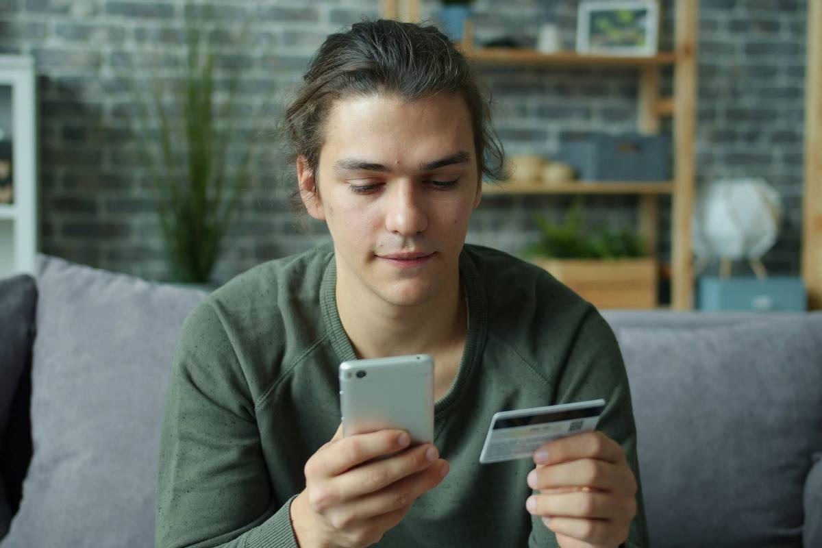 Person using a smartphone while holding a credit card.