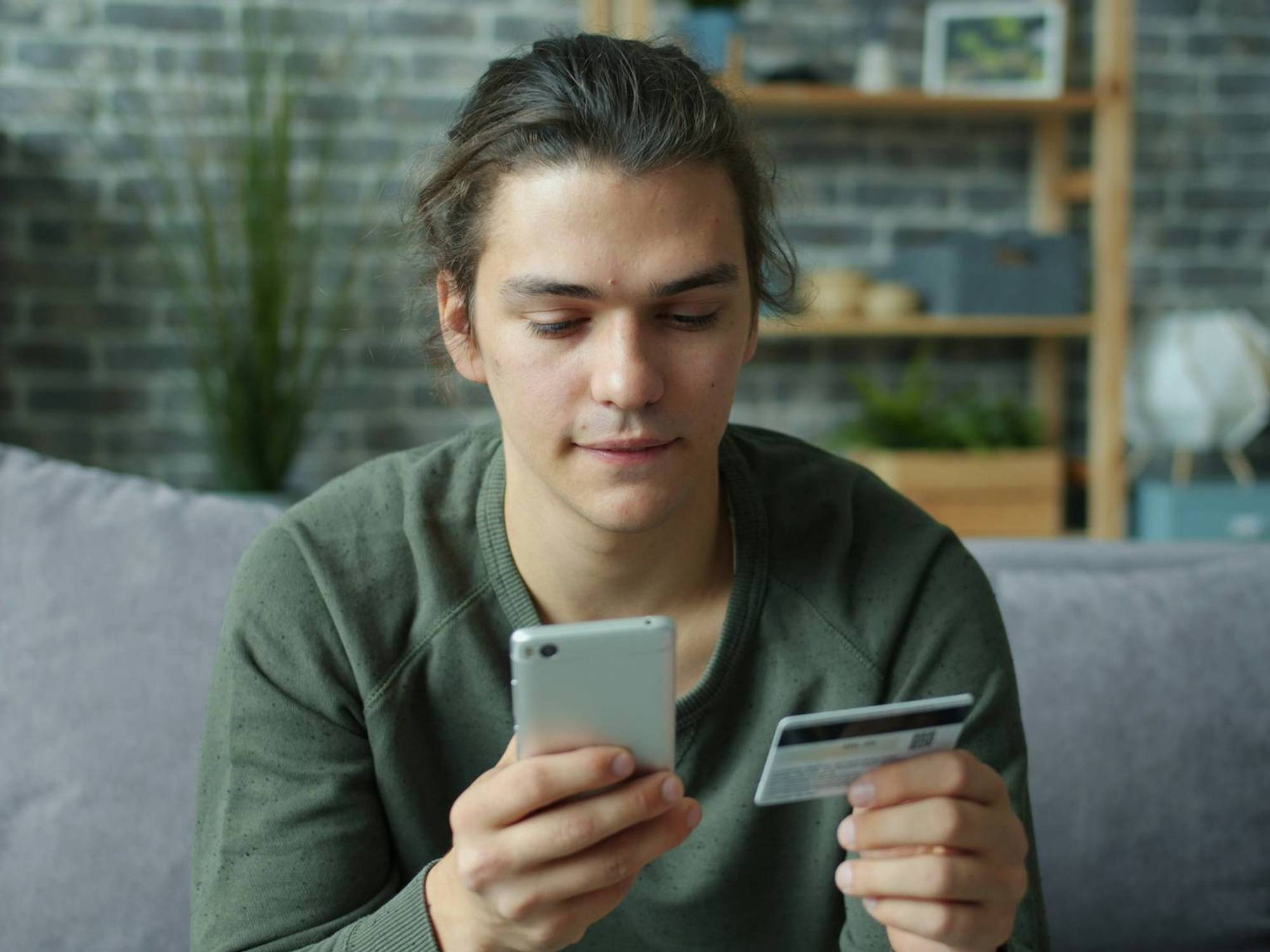Person using a smartphone while holding a credit card.