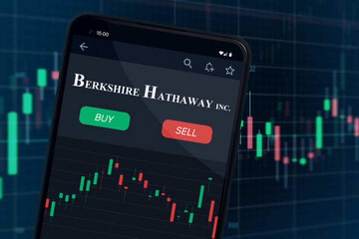 Phone screen showing "buy/sell" options for Berkshire Hathaway, with stock chart background.