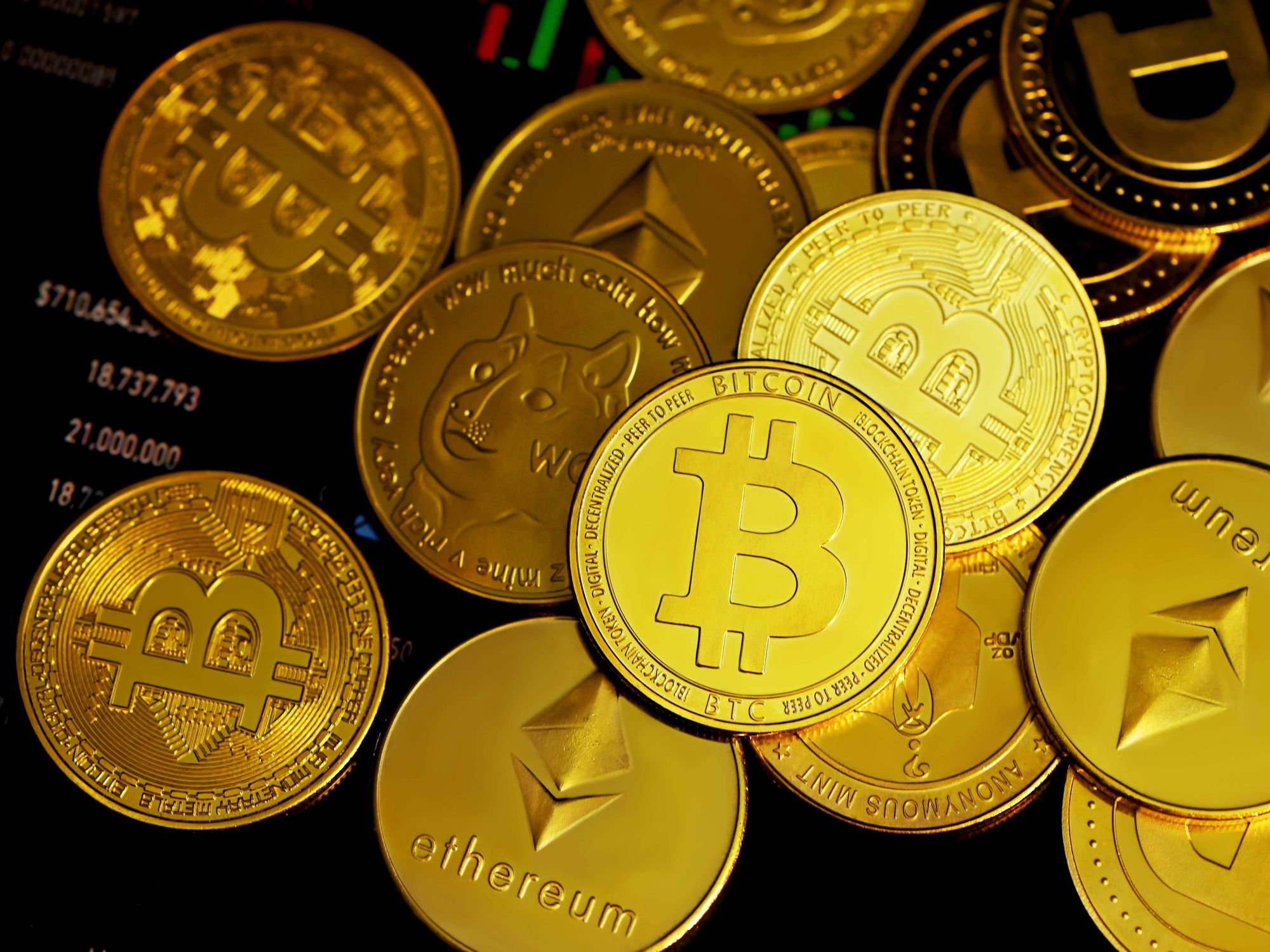Pile of gold coins with logos of different cryptocurrencies in a loose pile.