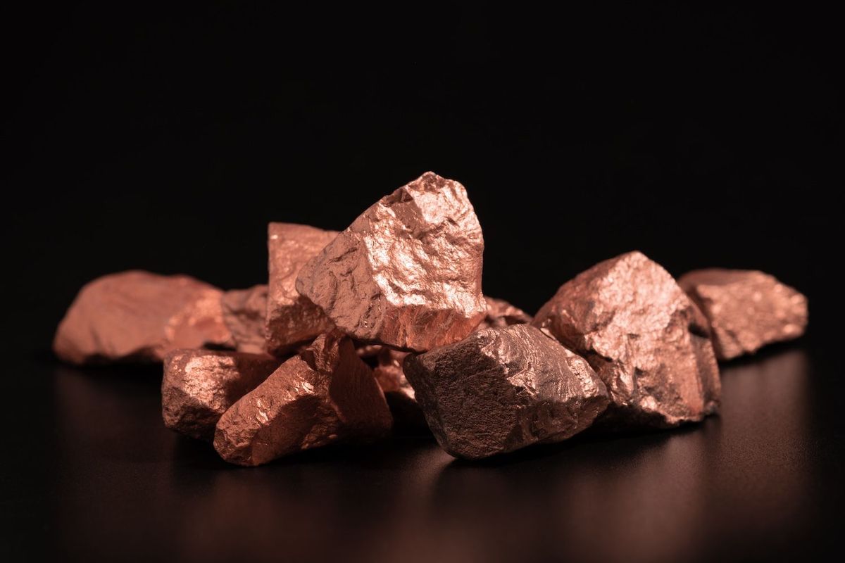 Pile of raw copper nuggets on a dark background.