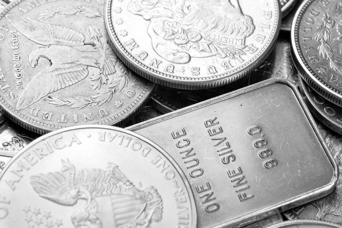 Pile of silver coins and a bar, featuring eagle and face engravings.