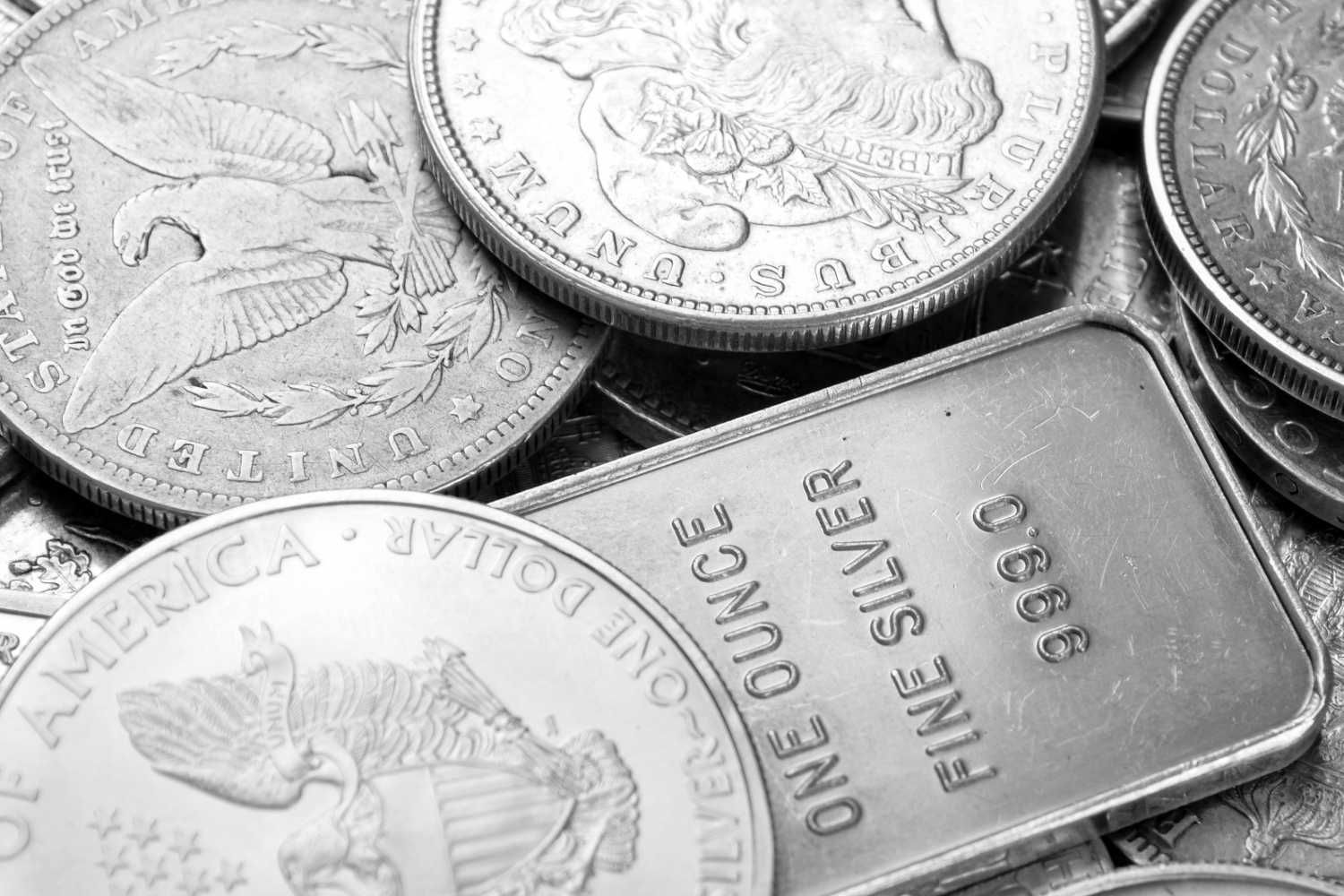 Pile of silver coins and a bar, featuring eagle and face engravings.