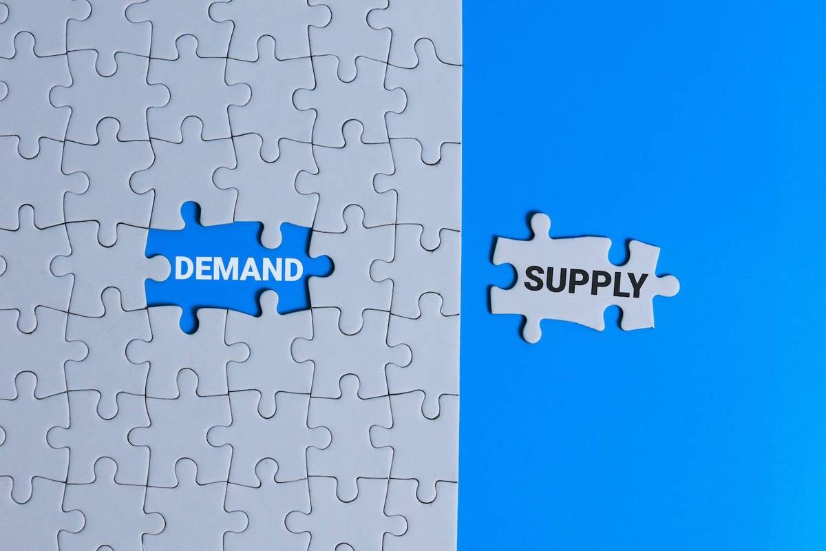 Puzzle with "Demand" missing piece, "Supply" piece on the side, blue background.