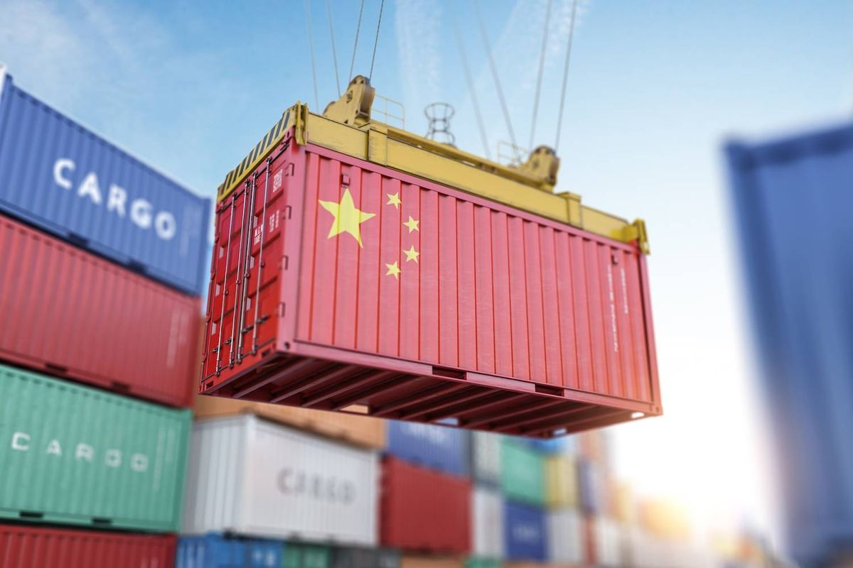 Red shipping container with Chinese flag being lifted by a crane.