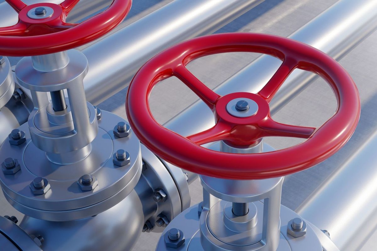 Red valve handles on industrial metal pipes.