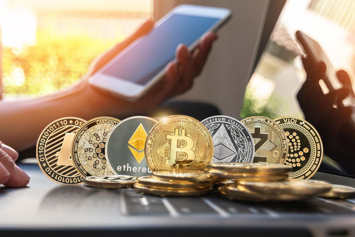 representations of various cryptocurrencies in coin form sitting on a laptop