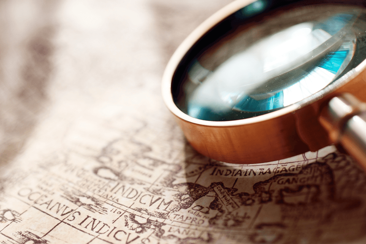 Retro copper-colored magnifying glass and old white nautical chart.