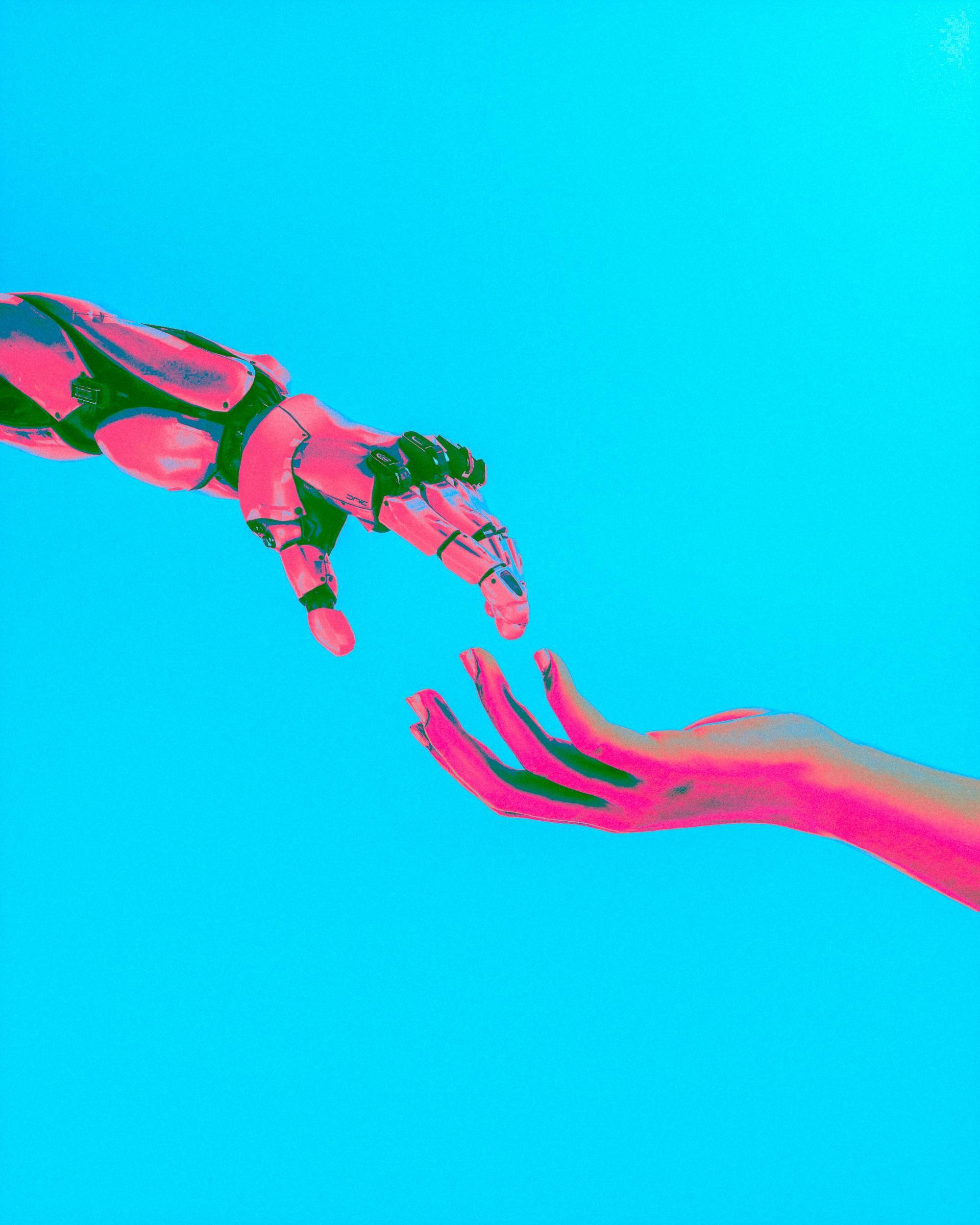 Robotic hand reaches toward human hand against a bright cyan background, both tinted in pink hues.