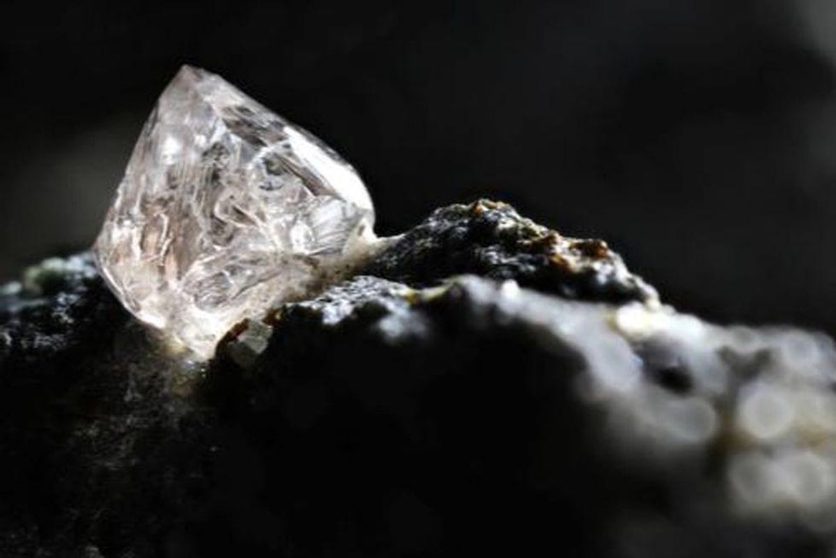 rough white diamond embedded in black rock