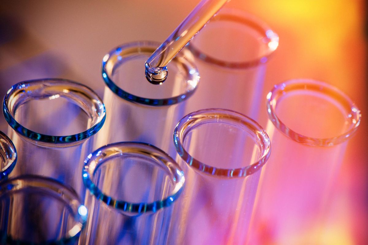 Row of test tubes and pipette with chemical droplet chemical coming from it.
