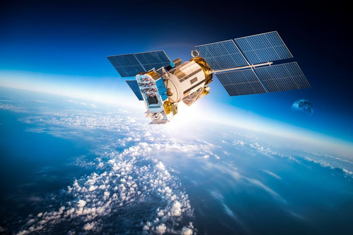 Satellite orbiting Earth with visible solar panels and distant planetary horizon.