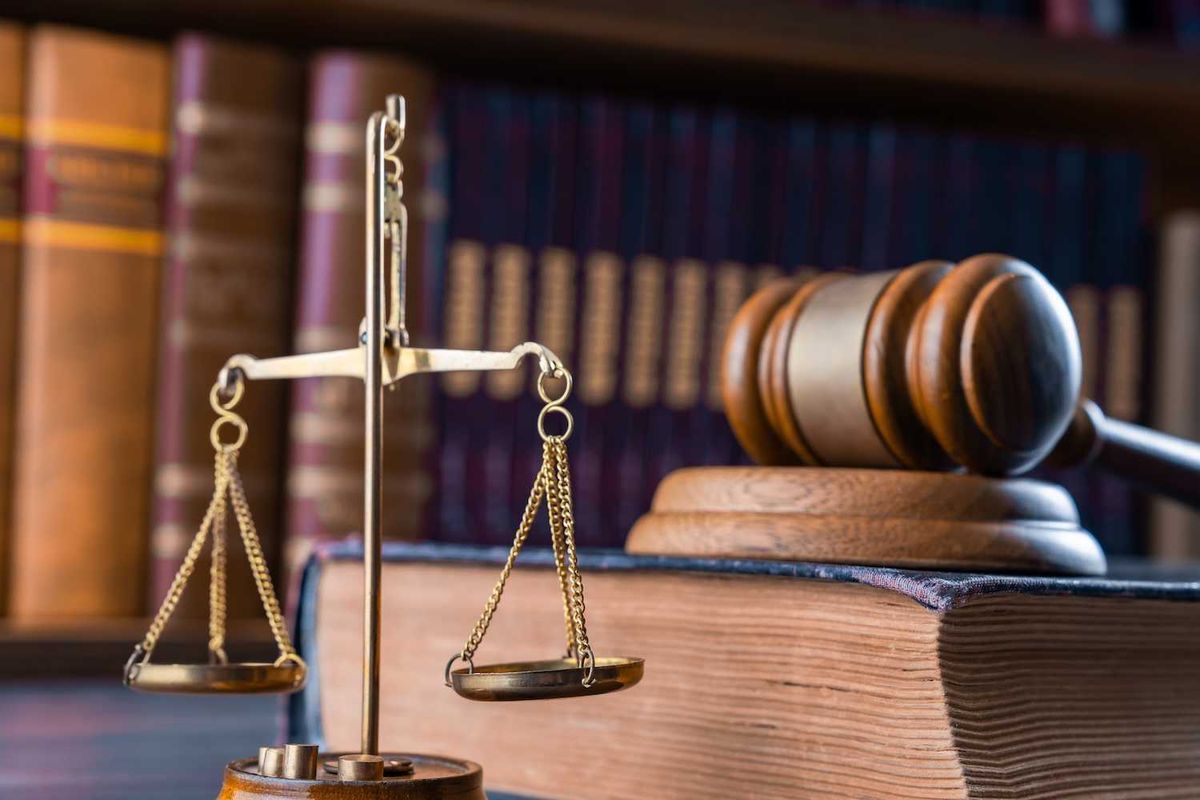 Scales of justice, gavel, and law books on a desk.
