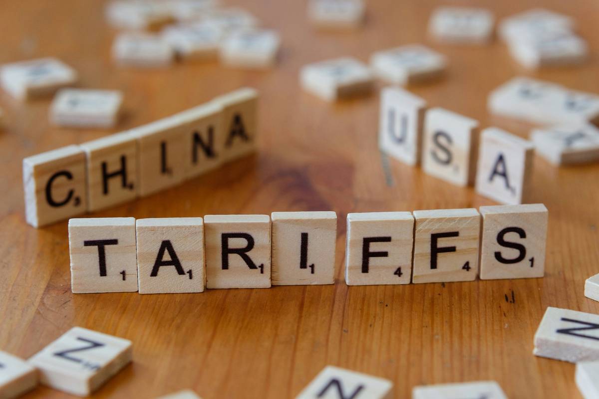 Scrabble tiles showing "TARIFFS" with "CHINA" and "USA" in the background.