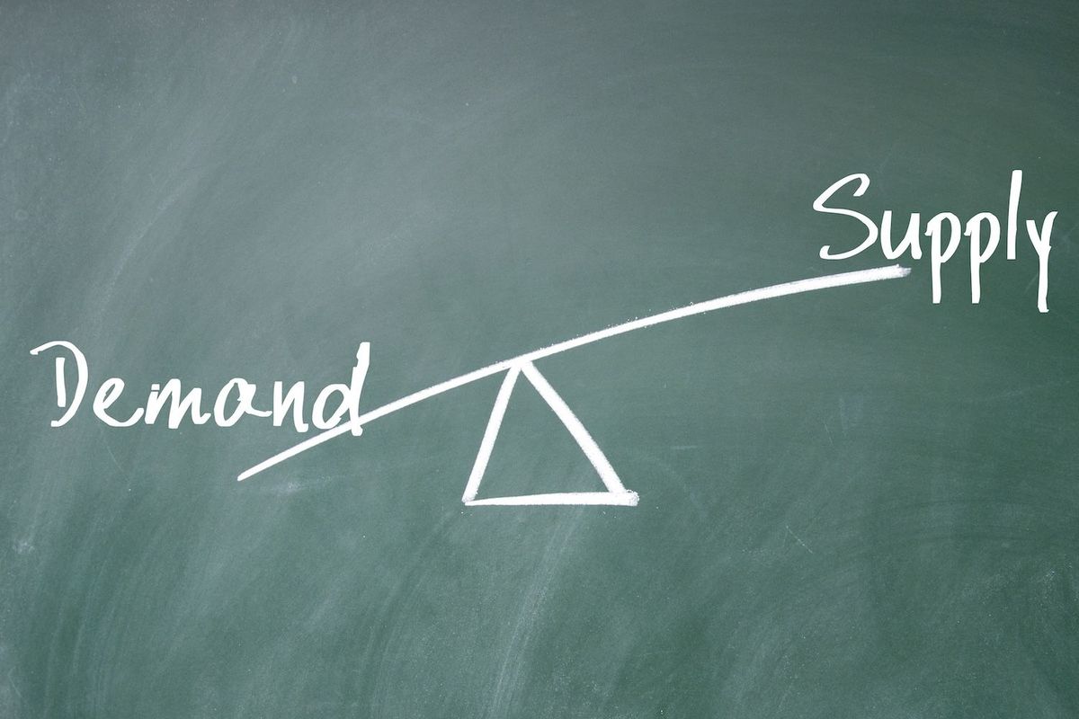 Seesaw diagram with "demand" outweighing "supply" on a chalkboard.