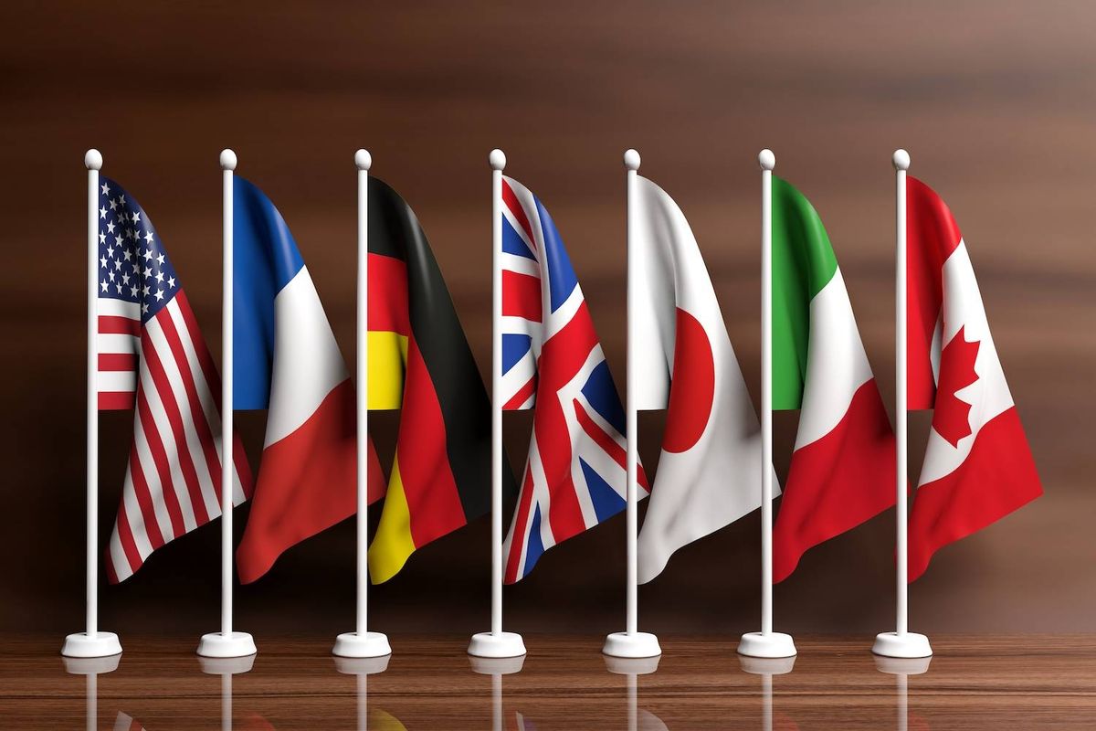 Seven flags of different countries in a row on a wooden table.