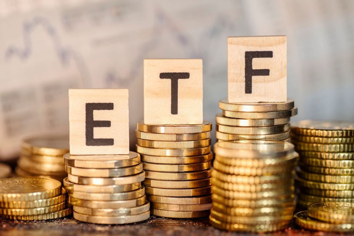 Several piles of coins at different heights. The middle three piles have wooden blocks on top with letters spelling ETF.