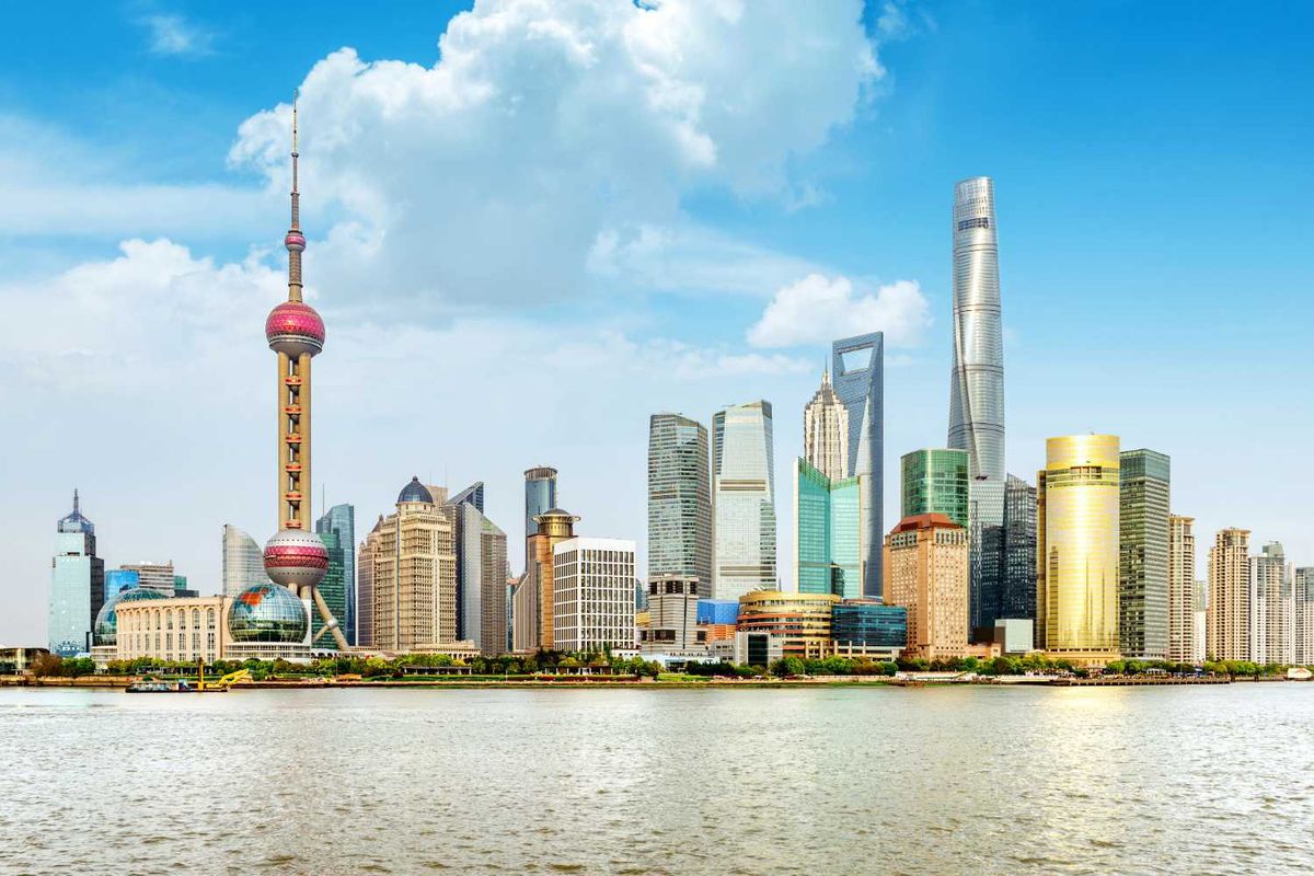 Shanghai skyline with modern skyscrapers and Oriental Pearl Tower by the river.