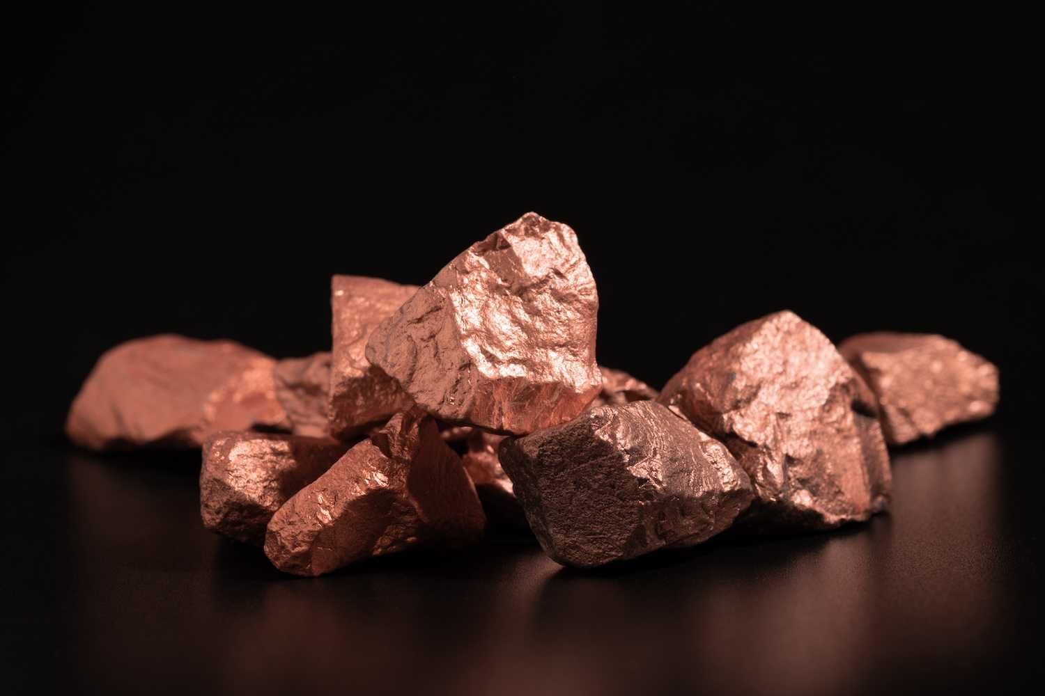 Shiny copper mineral rocks on a dark background.