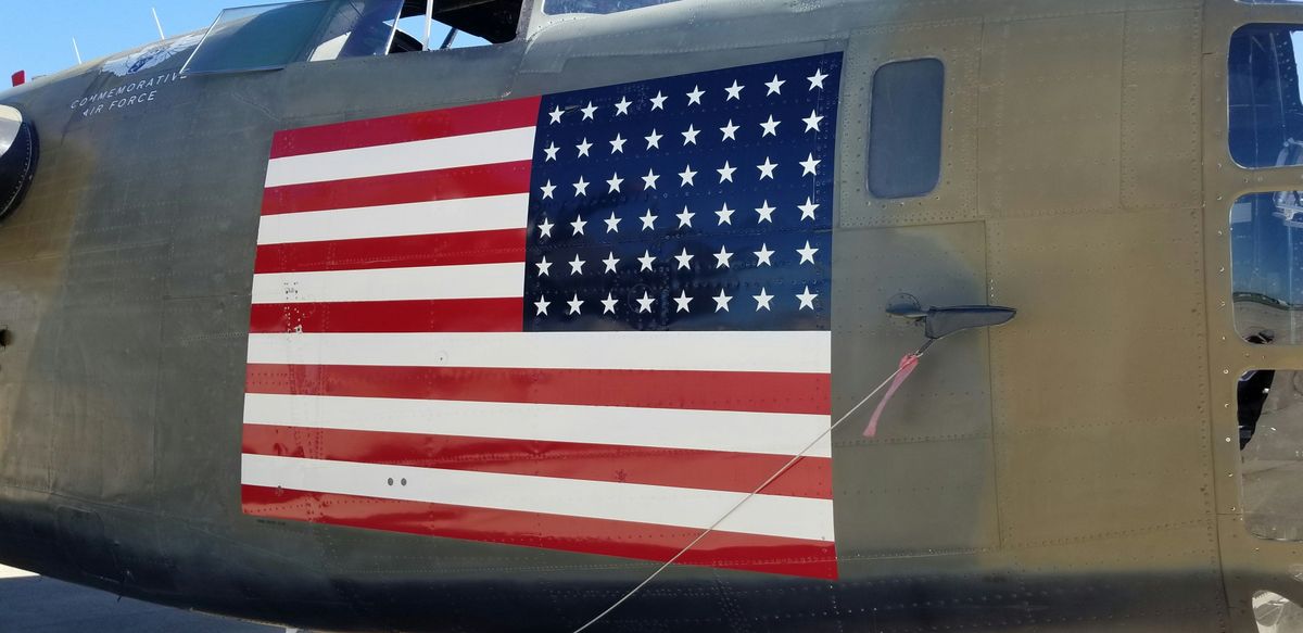Side view of a military plane with a large American flag painted on the fuselage.