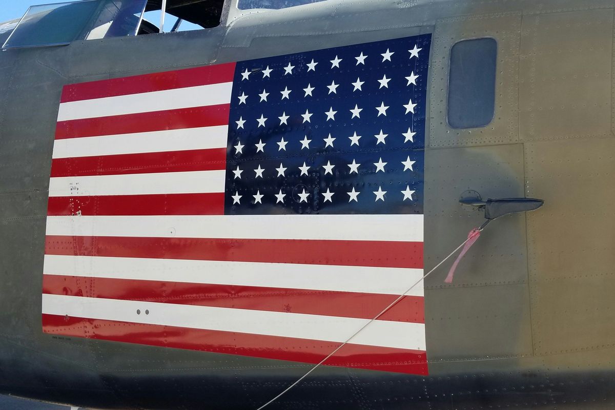 Side view of a military plane with a large American flag painted on the fuselage.