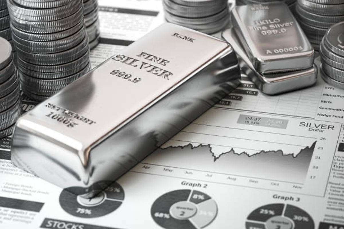 Silver bar and coins on top of silver stocks information sheet.