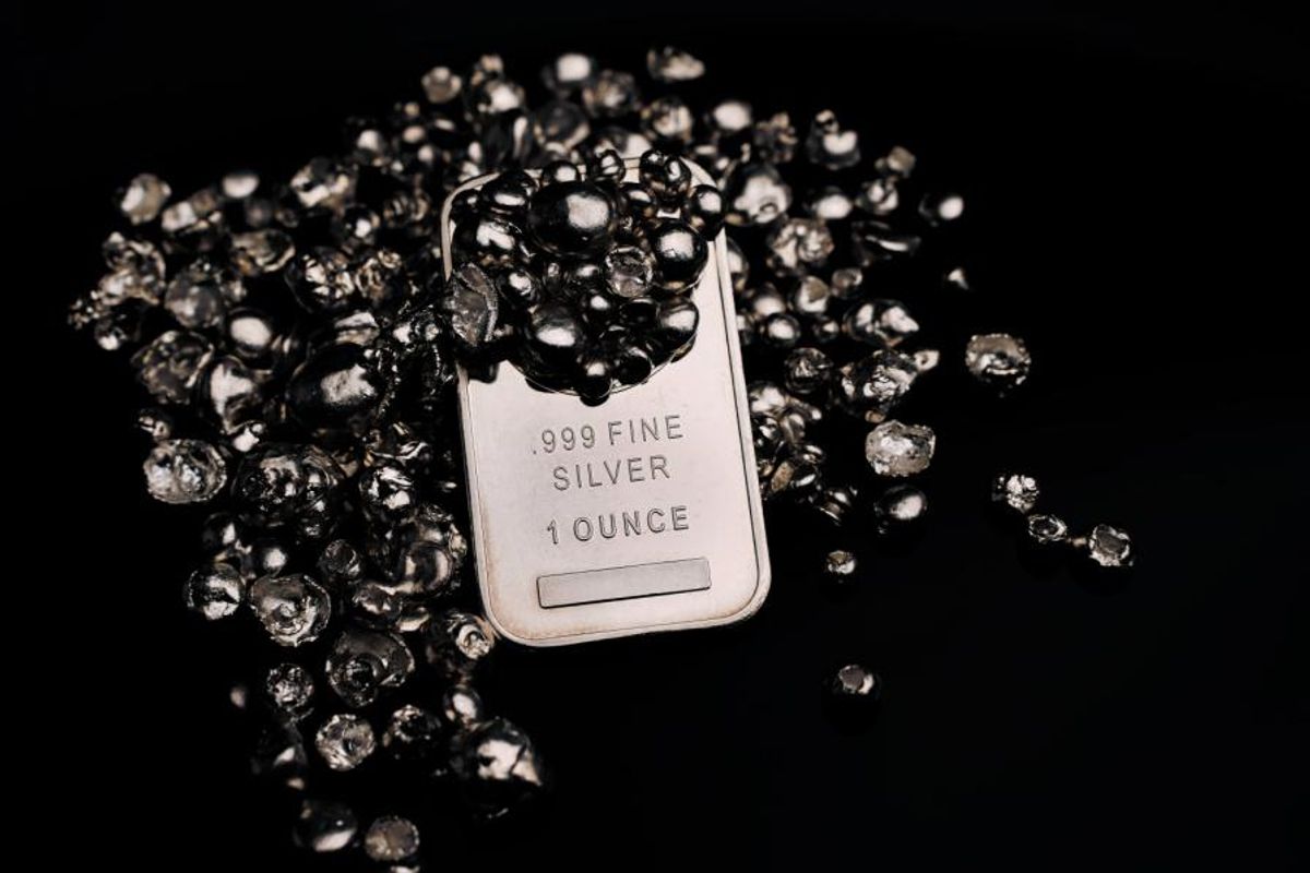Silver bar surrounded by shiny silver nuggets on a black background.