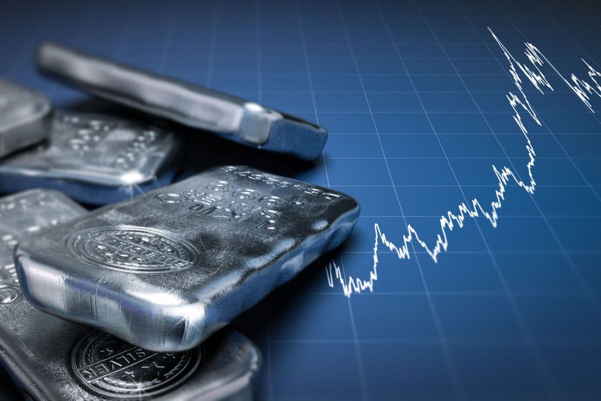 Silver bars in a pile on the left on top of a blue grid with a stock price chart in white.