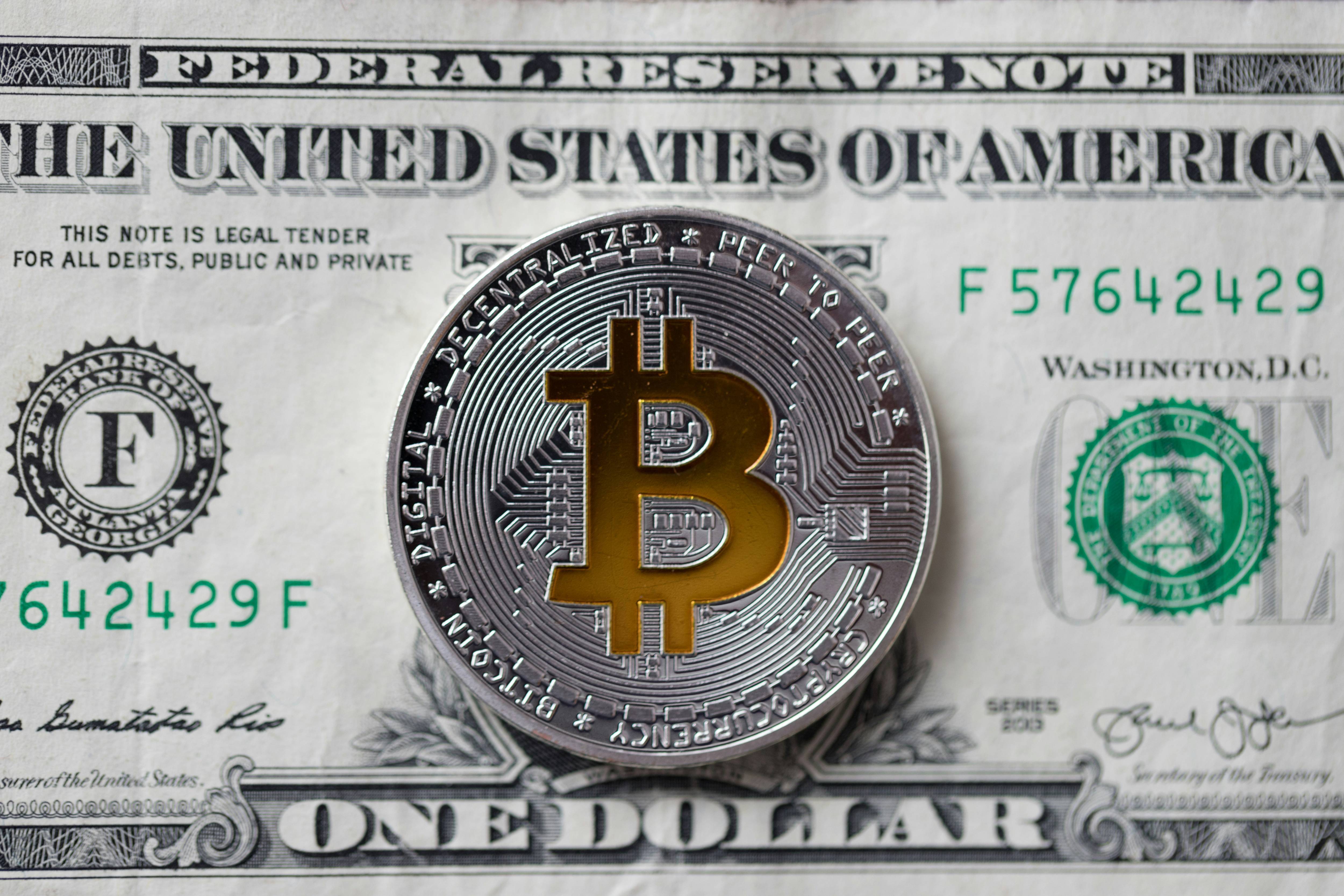 Silver Bitcoin sits on top of a US$1 bill.